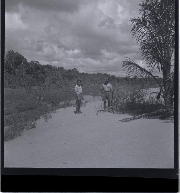 image of Black and white medium format negative of two men standing with palm beside them