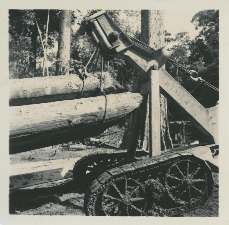 Image of Black and white print of a close up of a tractor lifting logs