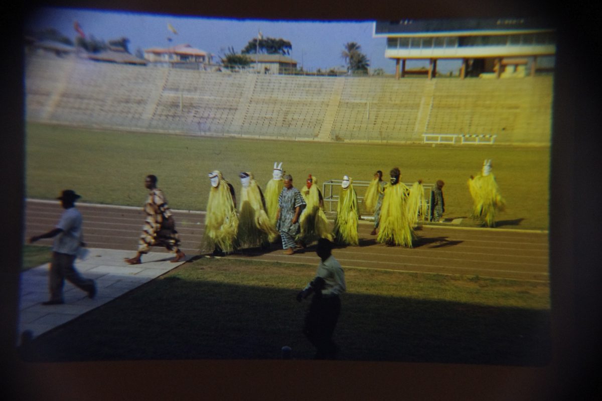 Photograph of crowd of people in yellow outfits walking through stadium.