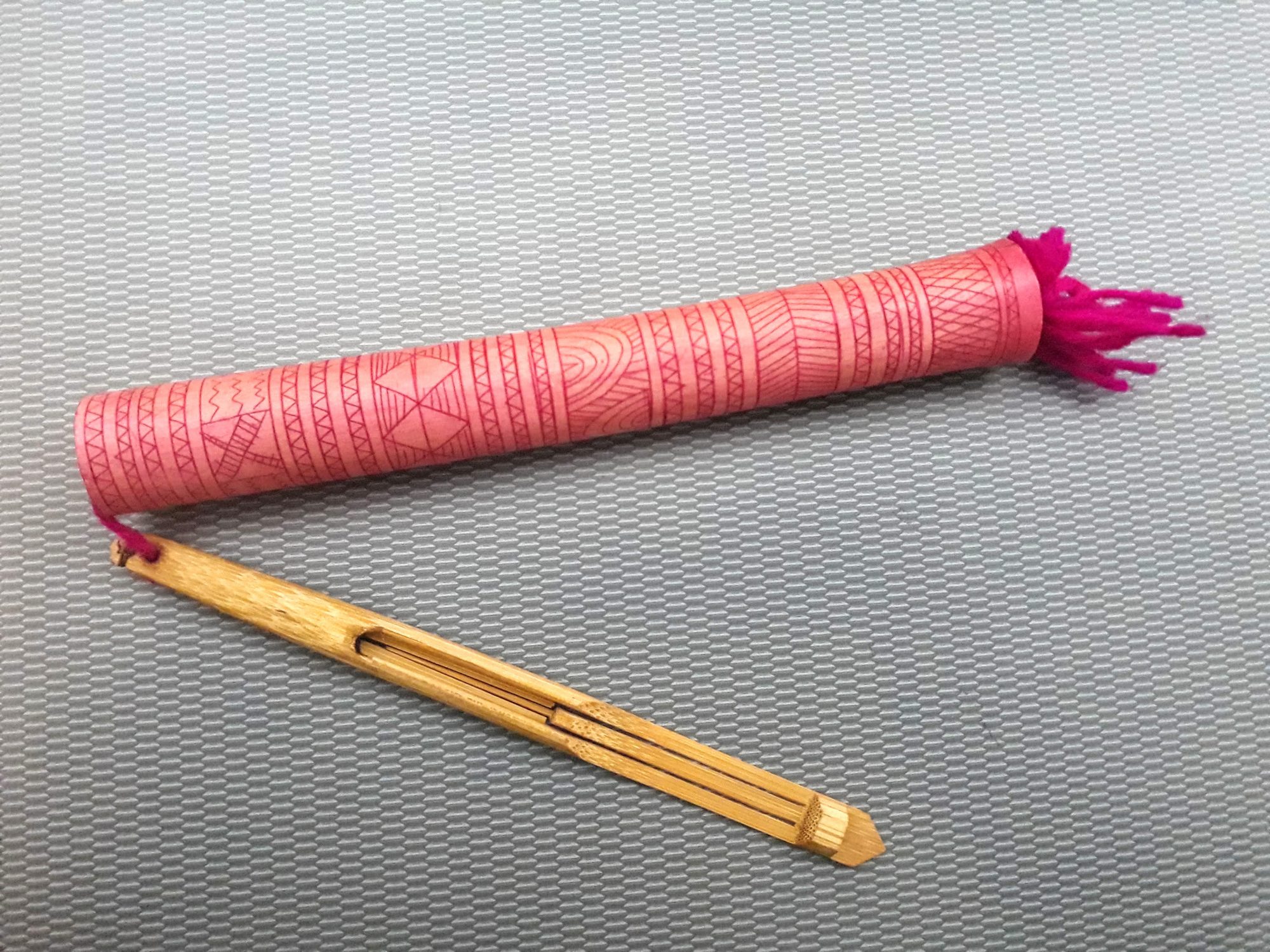 A small red tube attached to a piece of wood
