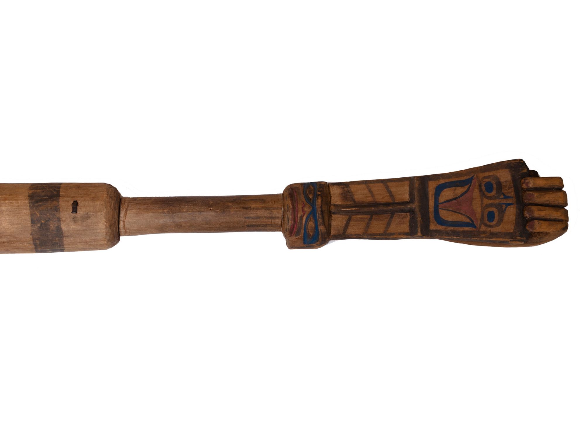 Long baton rattle, used by a dance leader, made of carved and painted wood. The top of the baton is carved in the shape of a hand, holding a panel on which a face is painted.