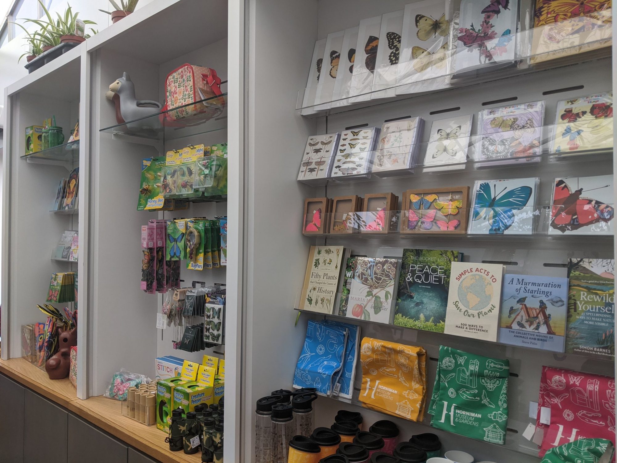 A display of goods in a shop, showing cards, pictures, tea towels, books and toys