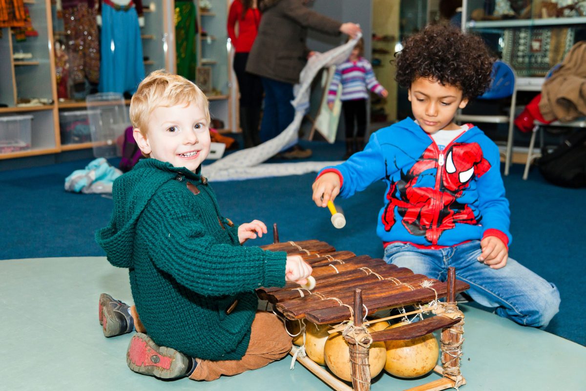 Two boys are playing on a wooden xylophone