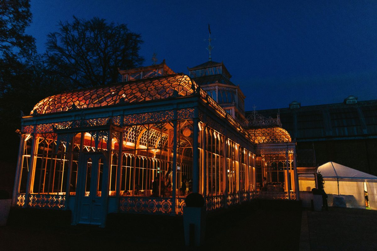 A conservatory lit up at night, as seen from outside