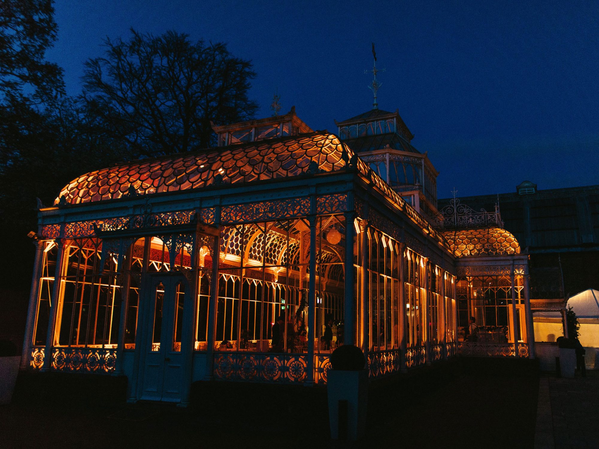 A conservatory lit up at night, as seen from outside