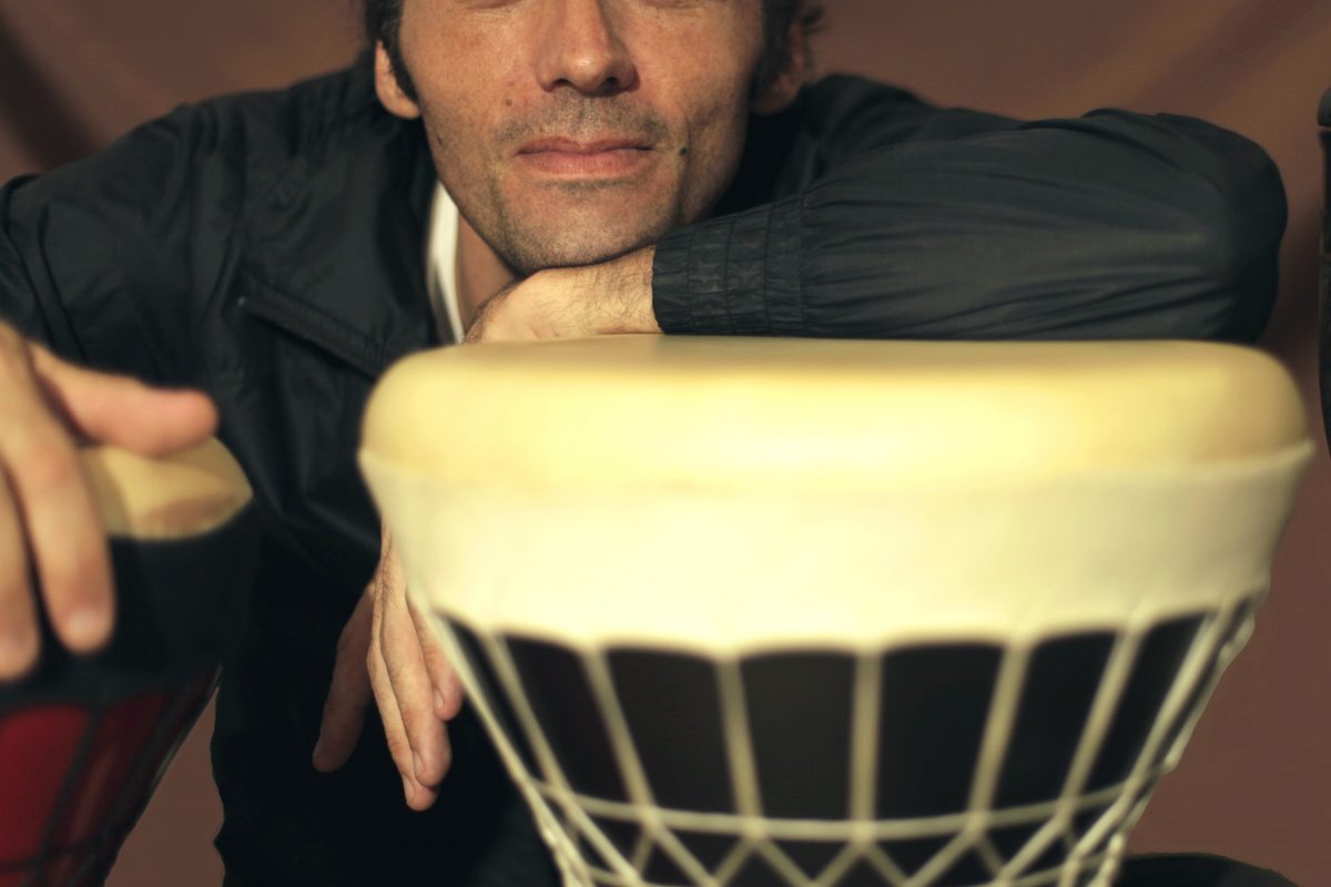 Musician Ant Romero leans on a drum and looks at the camera