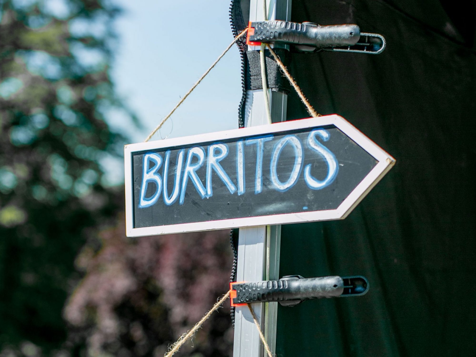 Signs hanging from a metal pole saying Burritos and quesadilla