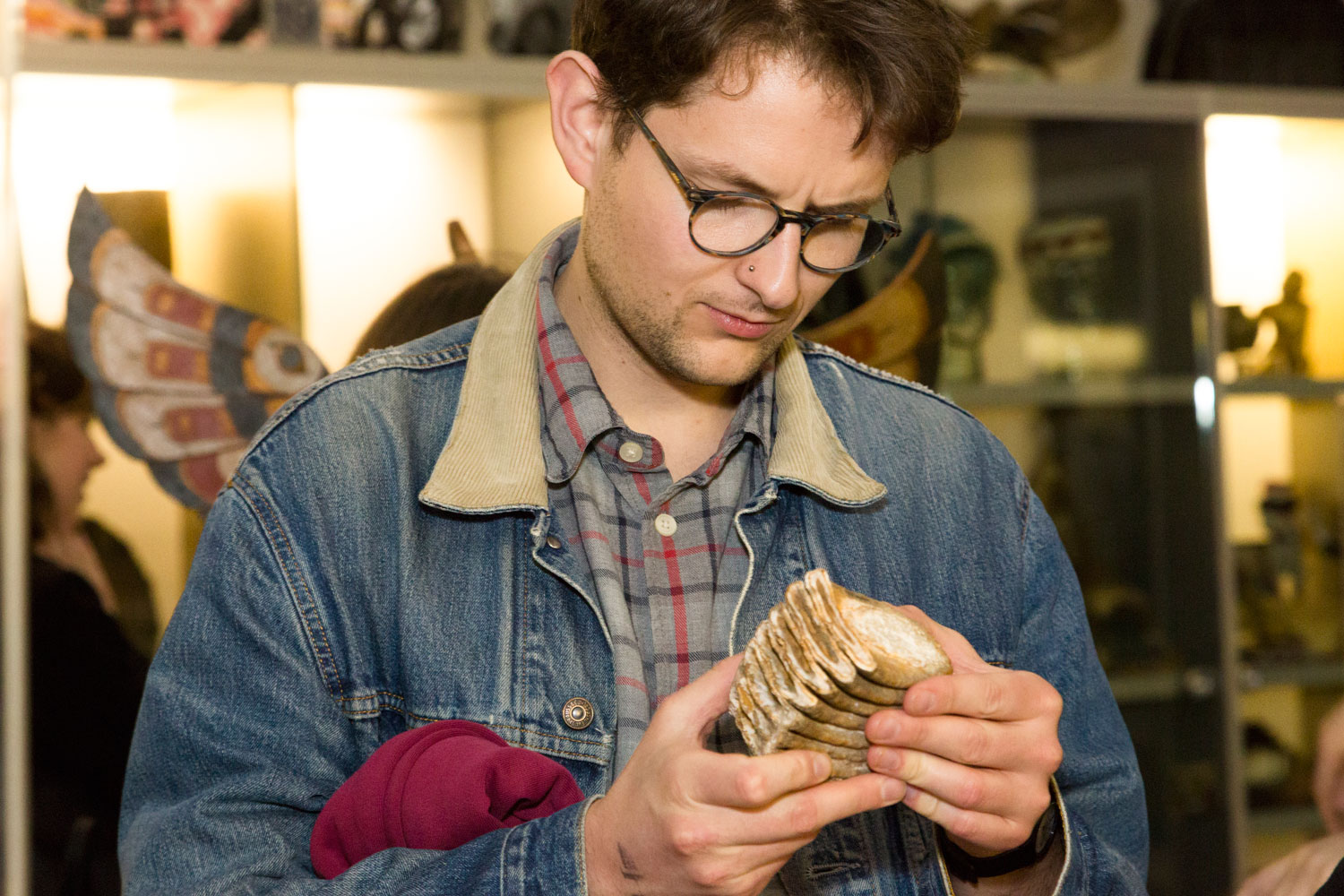 A man is holding an object which looks like a giant tooth and is considering it with a serious look on his face