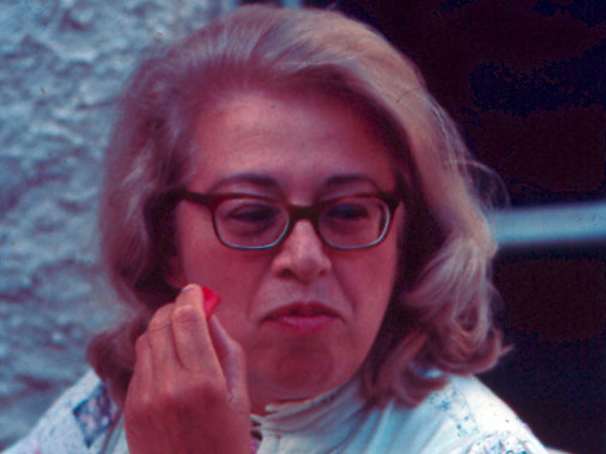 A dated image of a woman in a light dress eating red food