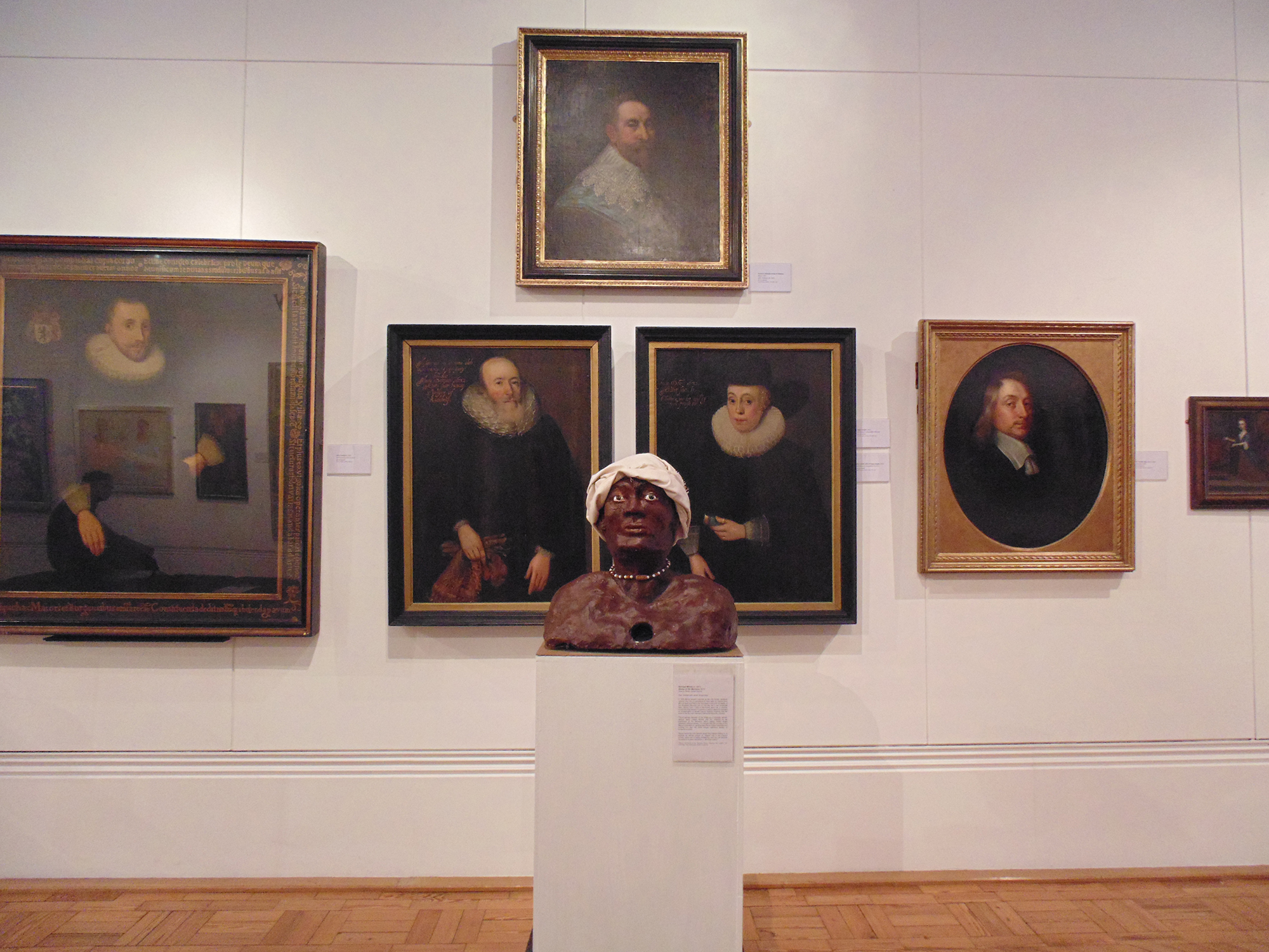 bust on a pedistol in a room full of paintings