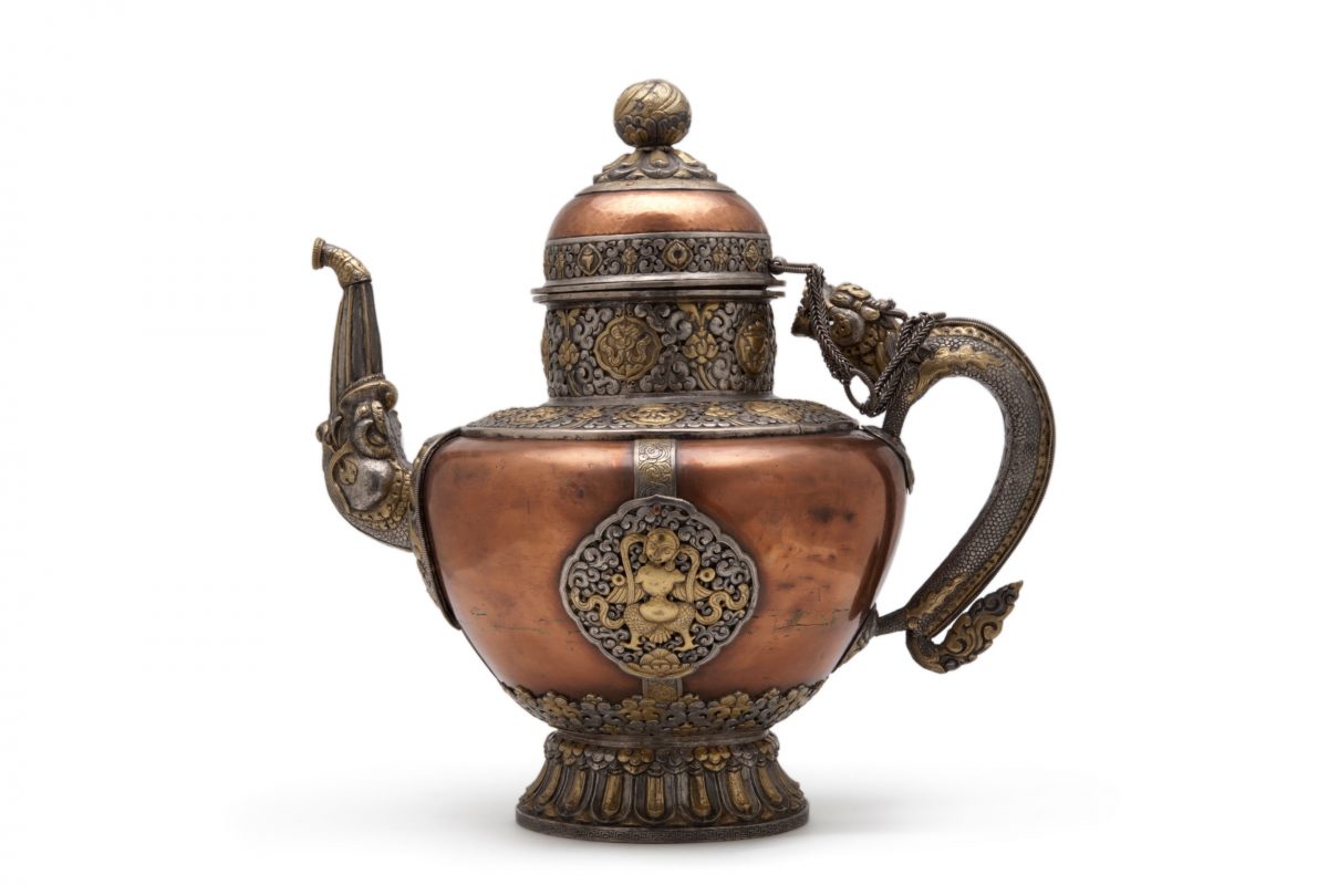 A highly decorated copper teapot with swirls and floral motifs