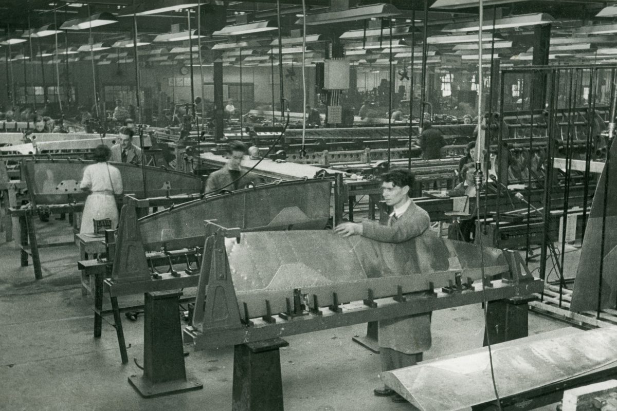 Main assembly shop - Spitfire ailerons. Black and white image of people working on plane parts.