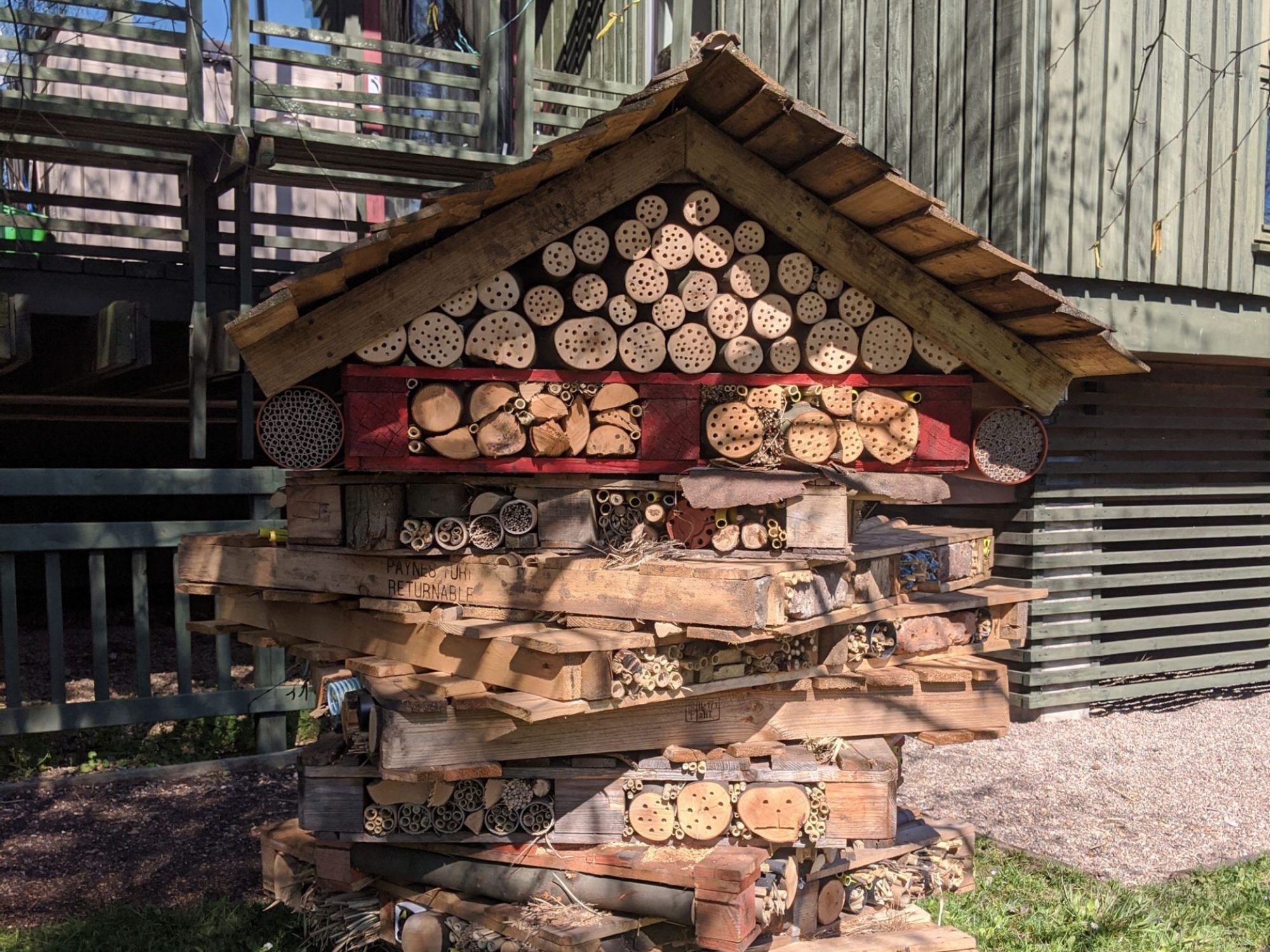 A close up of a bee house - wooden palettes and logs piled together to resemble a house