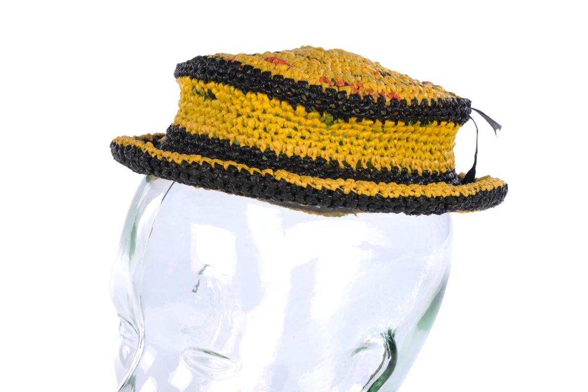 A black and yellow hat made of twisted plastic against a white background