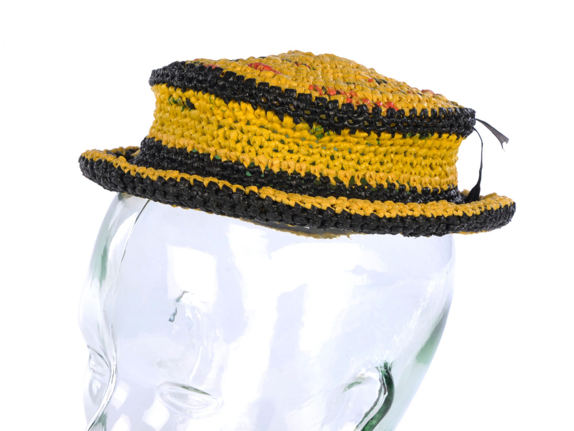 A black and yellow hat made of twisted plastic against a white background