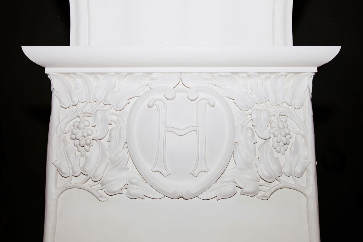 A close up of a white column decorated with white trees and vines