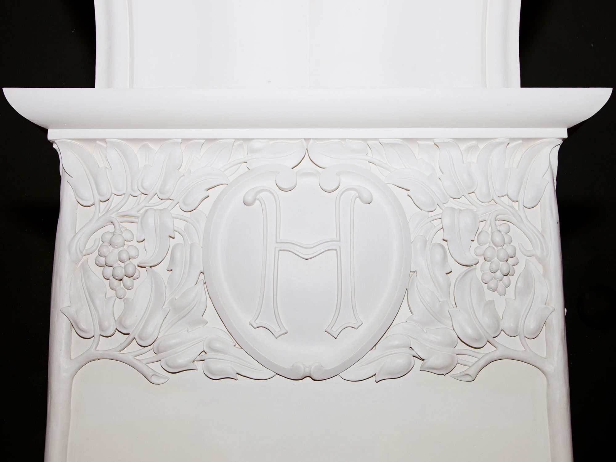 A close up of a white column decorated with white trees and vines