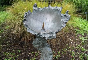 A sculptural bowl in a garden, acting as a sundial