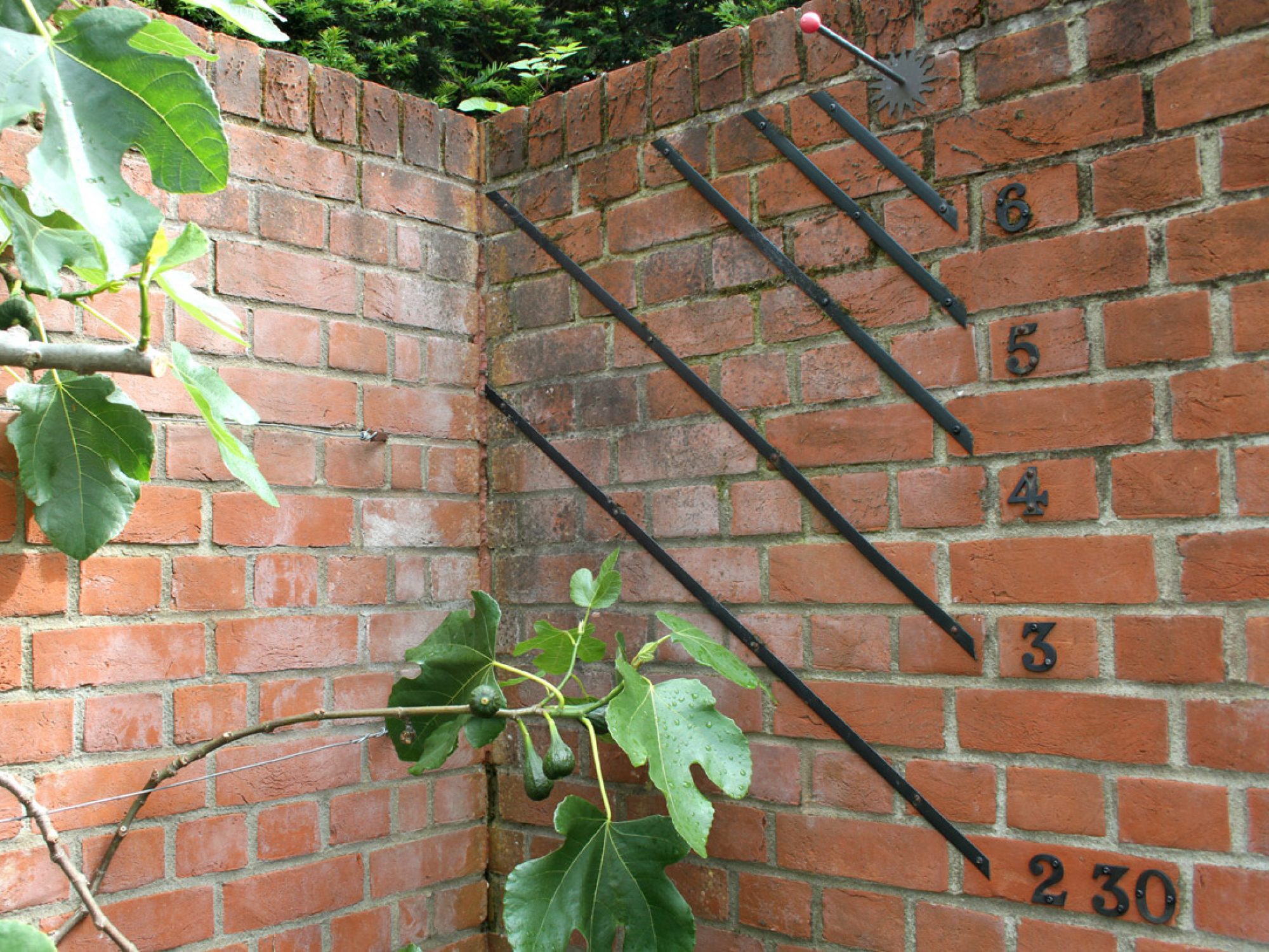 A wall corner with some black lines and numbers, indicating a sundial