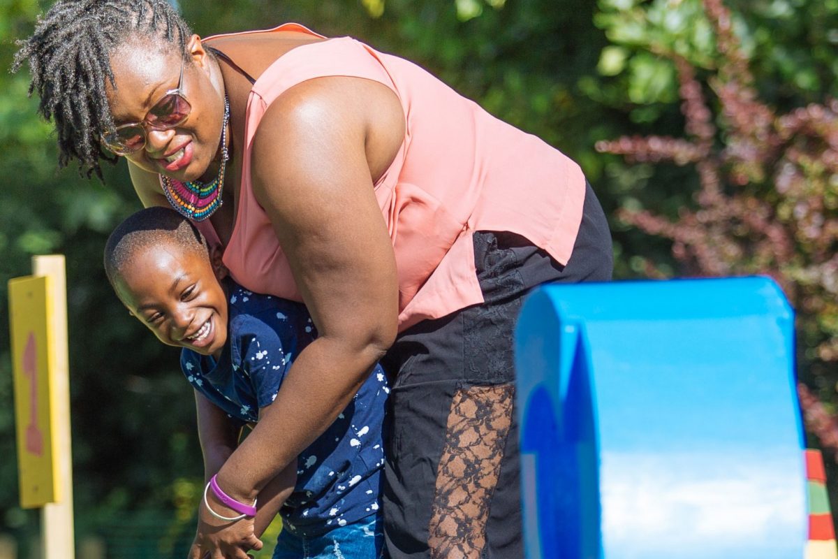 A woman helps a child putt a shot in golf