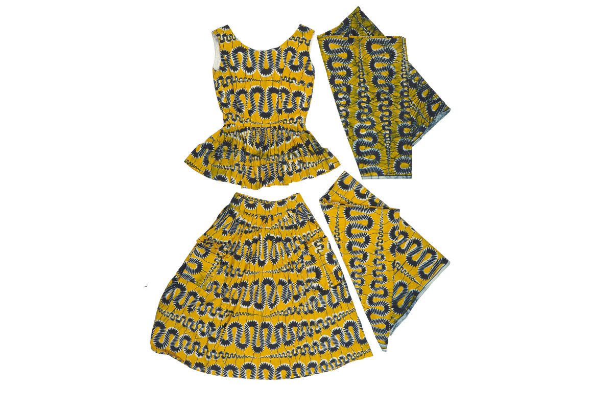 An outfit made from yellow and black printed fabric laid flat on a white background. There are four pieces: a sleeveless top, a skirt and two side swatches of fabric.