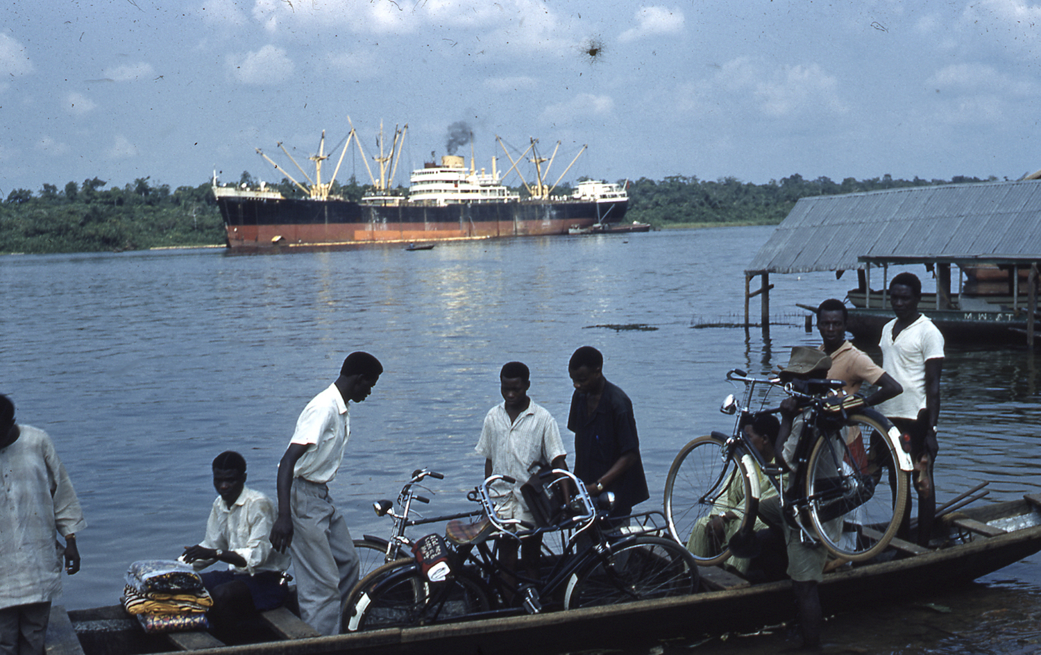 A group of boys on a canoe on the river with bikes.