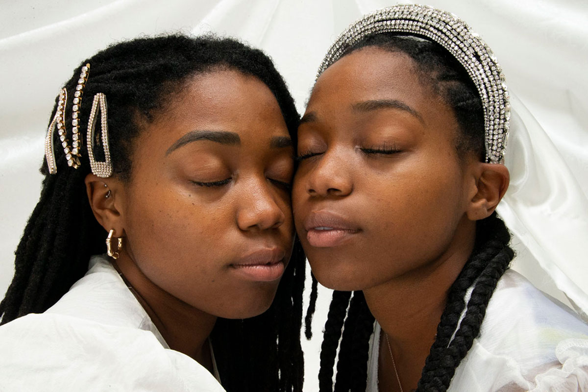 Two black women cheek to cheek with their eyes closed