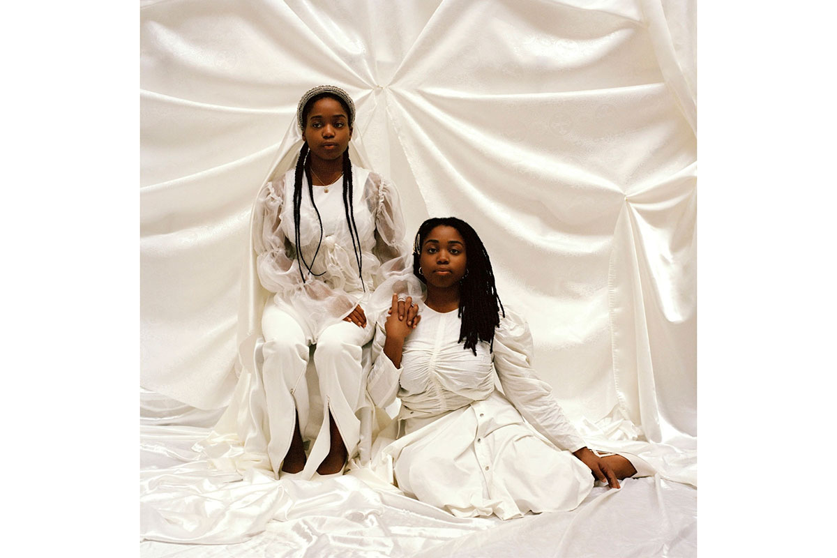 Two black women sitting, dressed in white