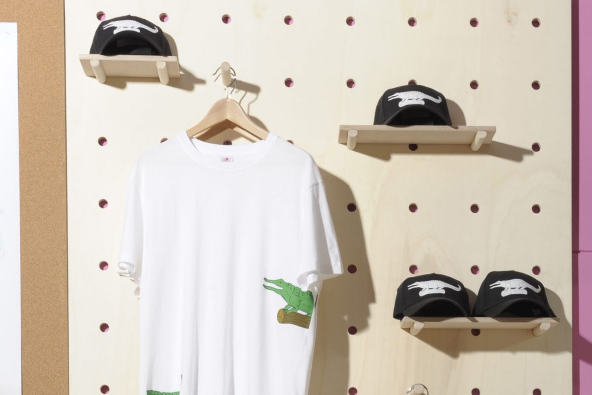 Tshirts hung up and trainers on shelves. The tshirts have illustrations of crocodiles on them