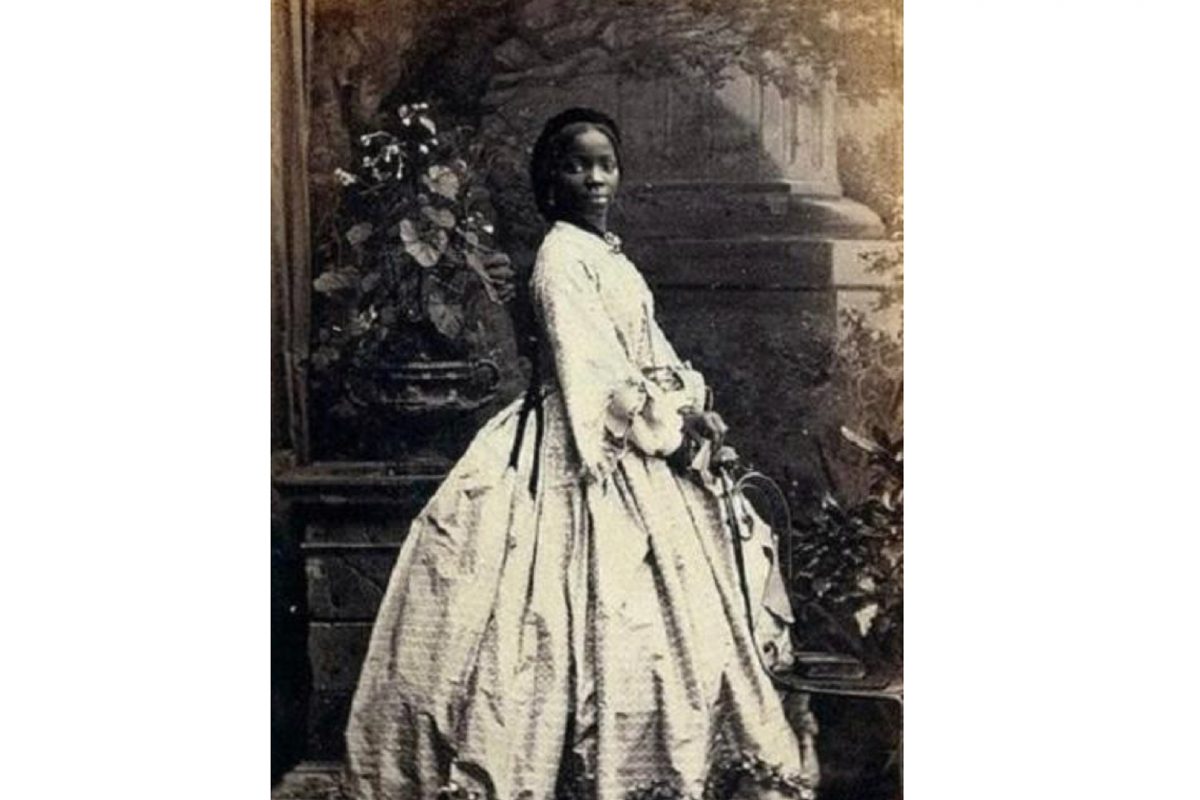 Black and white image of woman with long hair in period dress.