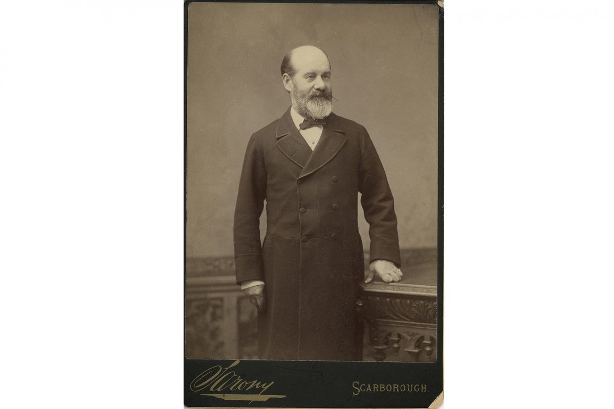 Black and white portrait of man in long black coat and bowtie