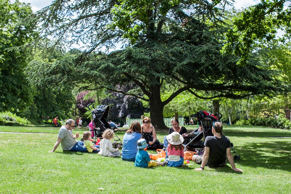 Large family sitting in Gardens enjoying picnic.