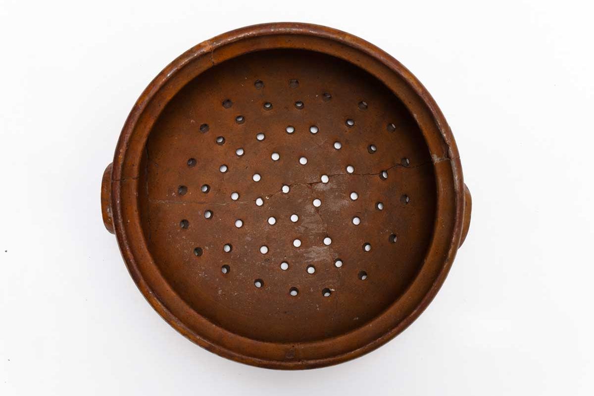 Image shows a ceramic strainer, with holes in the bottom