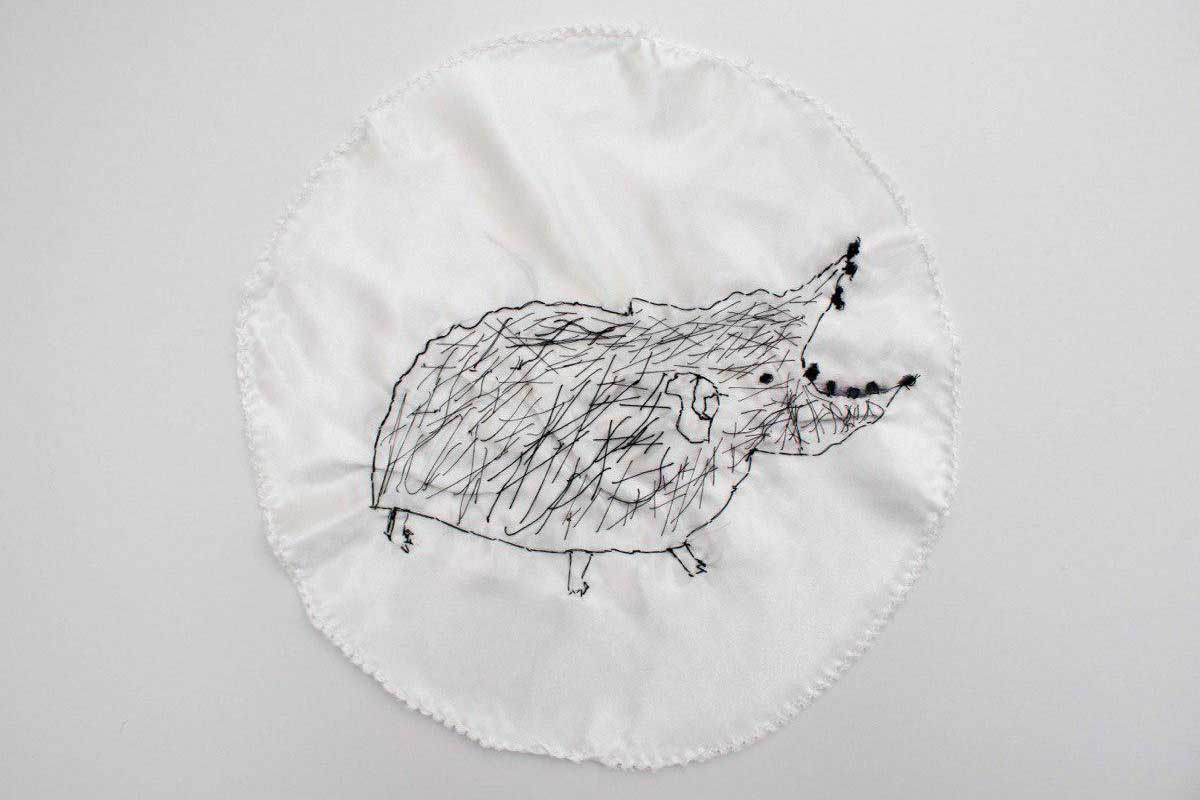 Embroidery of a drawing of a hairy creature with its mouth open