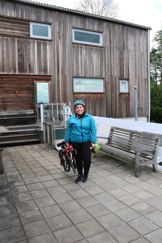 Charlotte stands next to her folded bike