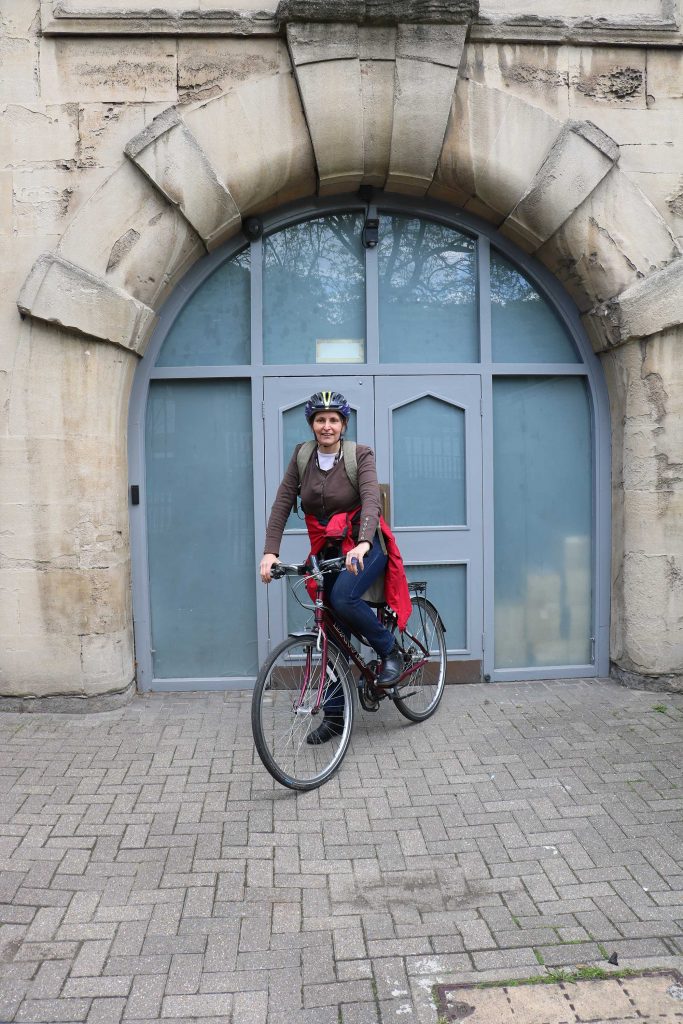 A woman sits on her bike in front of some double doors