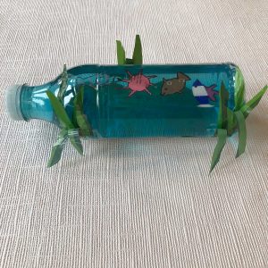 Plastic bottle filled with blue liquid and decorated with drawings of sea creatures