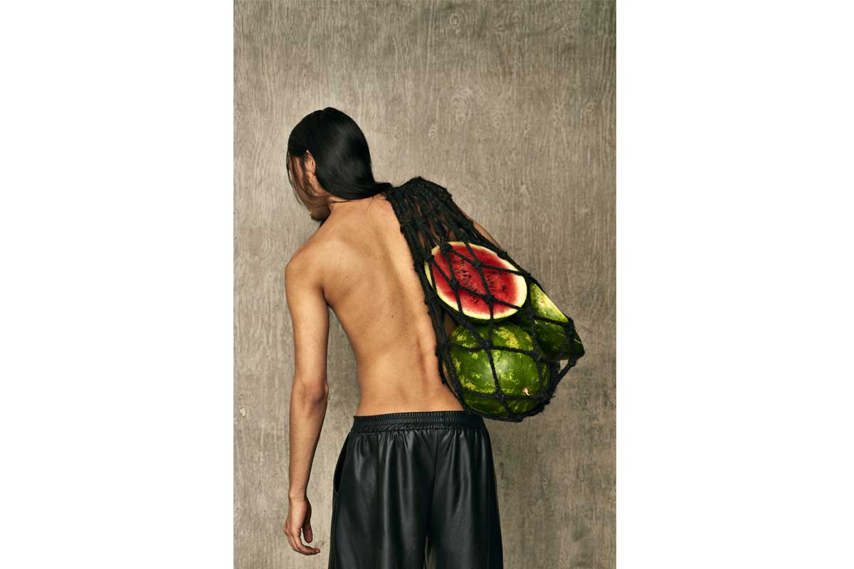 Man carrying a hair net bag, holding watermelons