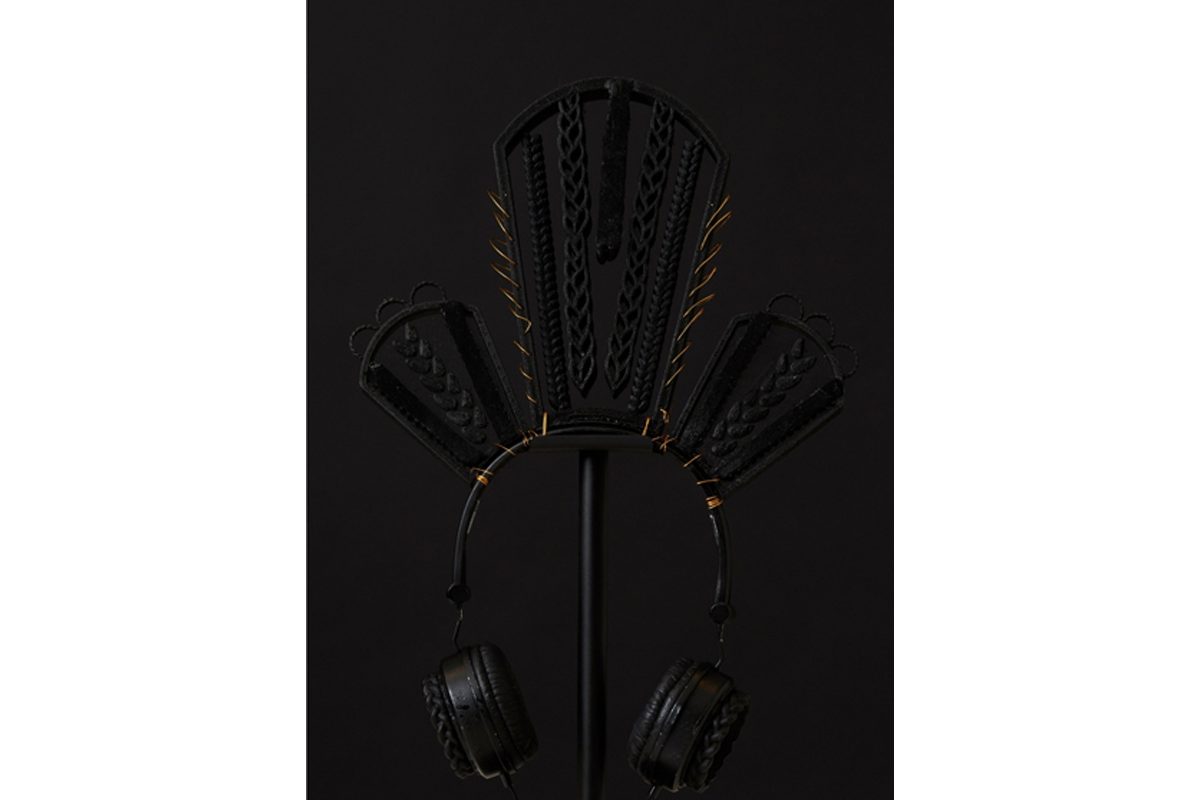 Black headphones with hair woven into three shapes at the top, a taller shape in the middle.