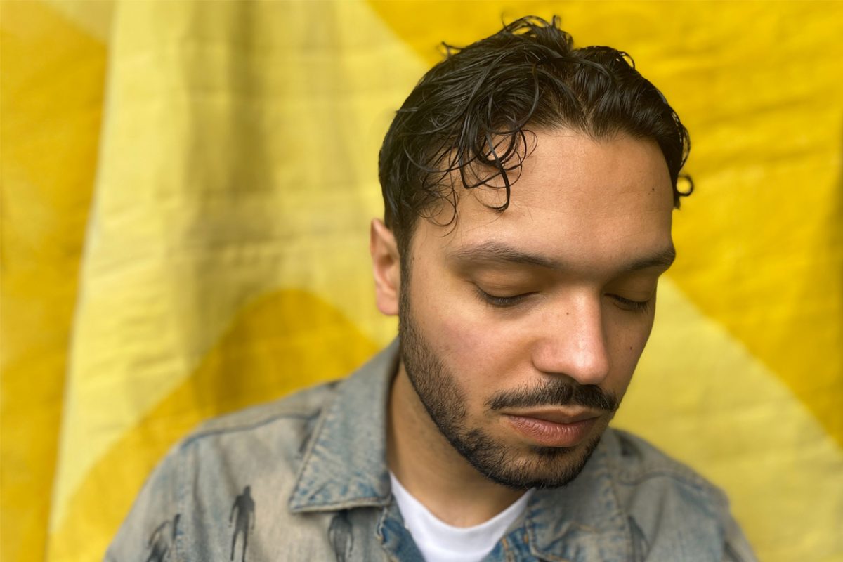 Jacob Goff, a Black man with short curly hair slicked back, sits against a yellow background with his eyes closed