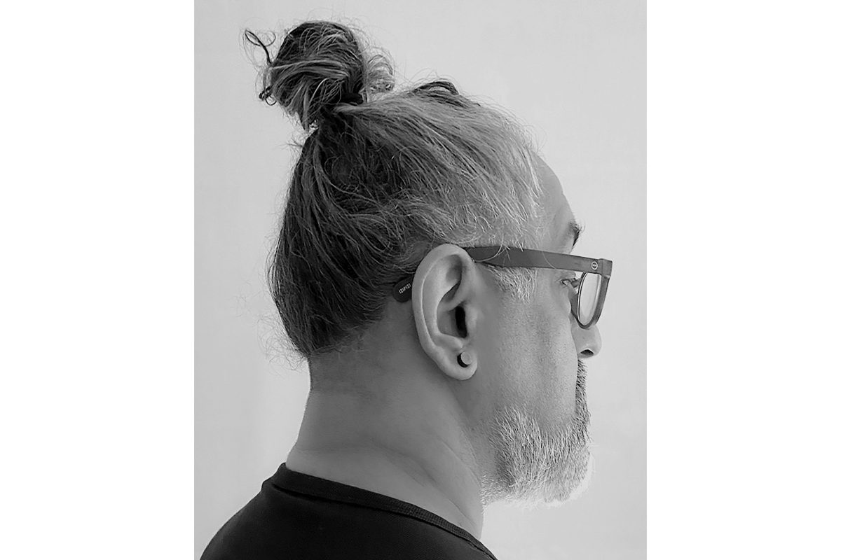 The right hand side of a man's face whose hair is in a topknot