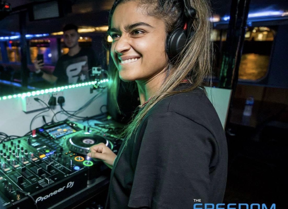 Woman turns and smiles behind her as she DJs