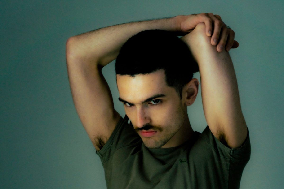 Man with arms above his head and wearing a green tshirt