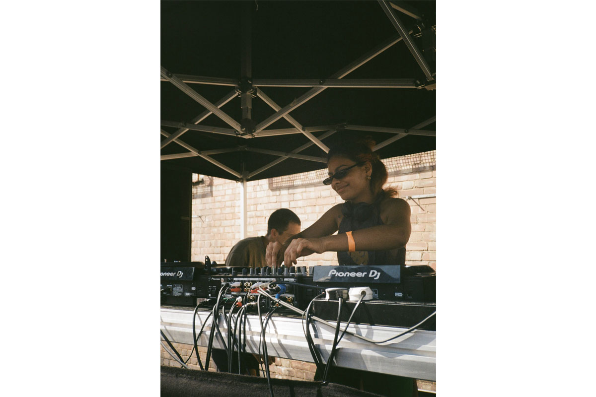 A woman DJs at some decks set up outside