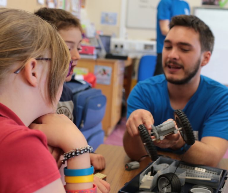 A man shows two children part of a car model