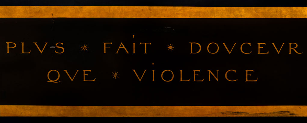 Close up of inscription on clavichord which reads 'Plus fait doucer que violence'