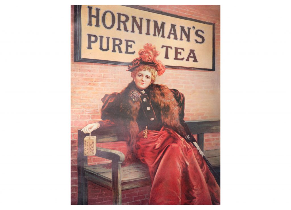 A historic advert for Horniman's Tea: a woman in Edwardian dress holds a package of Horniman's Tea in front of a Horniman's Tea sign