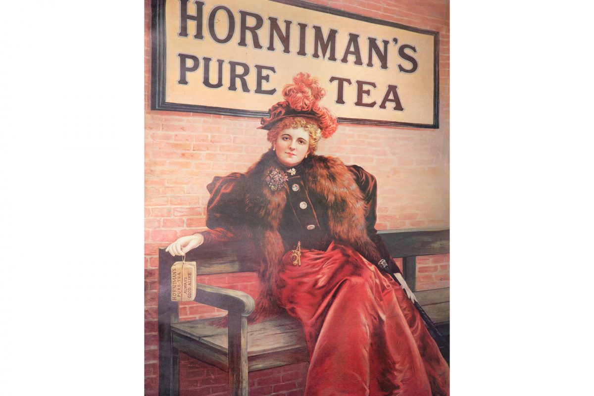 A historic advert for Horniman's Tea: a woman in Edwardian dress holds a package of Horniman's Tea in front of a Horniman's Tea sign