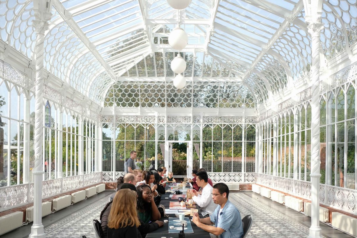 People sat at a long table inside the Horniman Conversatory