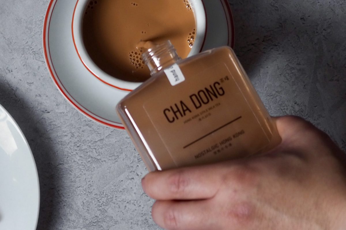 Square glass bottle labelled 'CHA DONG' being poured into a tea cup